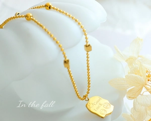 Detail of 18K gold plated necklace with square beads and Good Luck smiley face pendant