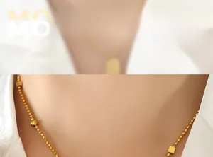 Close-up of golden beaded necklace with geometric square charms on a female model