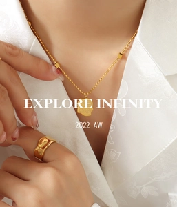 Close-up of gold geometric smiley pendant necklace and irregular wavy band ring