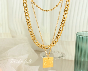Close-up of a layered gold necklace featuring a minimalist female figure engraved pendant
