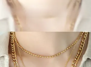 Close-up of layered gold bead and curb chain necklaces on model neck show