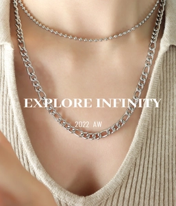 Detail of layered silver necklaces with bead and Figaro chains on a model's neckline