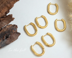 Gros plan de boucles d'oreilles géométriques en U dorées sur fond de bois rustique