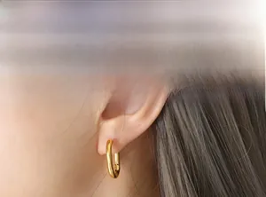 Gros plan sur boucle d'oreille dorée minimaliste en U plaquée or 18 carats