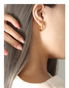 Gros plan de boucles d'oreilles géométriques en U plaquées or 18 carats sur modèle