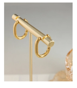 Gros plan de créoles dorées géométriques en forme de U sur un support de bijoux en métal