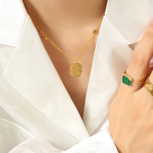 Gold stainless steel square smiley face necklace and ring set on white shirt