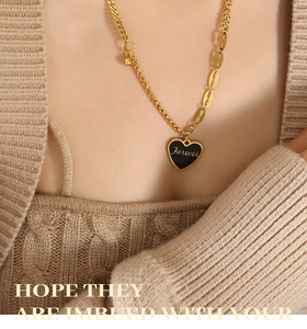 Macro view of golden heart pendant with Forever engraving on a steel ball chain
