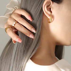 Élégantes boucles d'oreilles en U dorées et bagues minimalistes pour femme sur mannequin