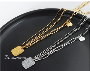 Detail view of gold and silver layered chains with heart and engraved square pendant