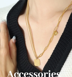 Close-up of double-layer golden chain necklace with heart and rectangle charms on a model