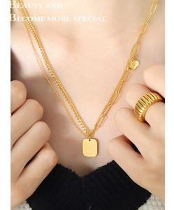 Detailed view of gold layered heart and square pendant necklaces with a ribbed metal ring