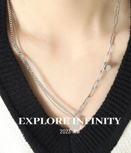 Detail of layered silver necklaces with engraved square pendant on a V-neck sweater