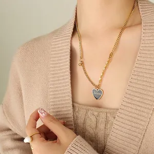 Gold necklace with black Forever heart pendant and pearl ring shown on model wearing knitwear
