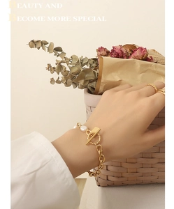 Close-up of gold OT buckle bracelet with freshwater pearl and geometric square pendant