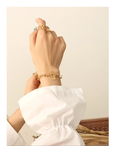 Detail view of OT toggle gold chain bracelet with freshwater pearl and square pendant