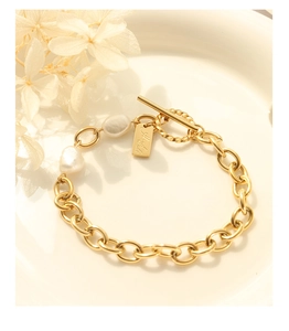 Macro view of gold chain bracelet with freshwater pearls and Hand made charm tag
