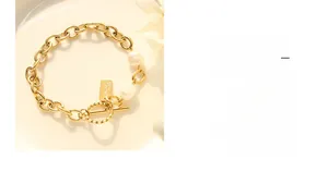 Detailed macro view of OT buckle gold chain bracelet with baroque pearls and handmade tag