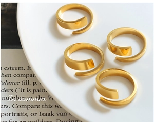 Detail of four minimalist spiral rings in polished 18K gold plating on a white plate