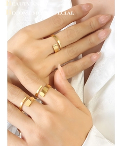 Detail of 18K gold-plated minimalist twist ring worn with silk clothing backdrop