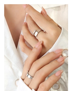 Macro shot of minimalist silver twisted rings with polished geometric facets on hand
