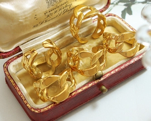 Macro shot of five gold chunky chain rings on red velvet luxury jewelry display box
