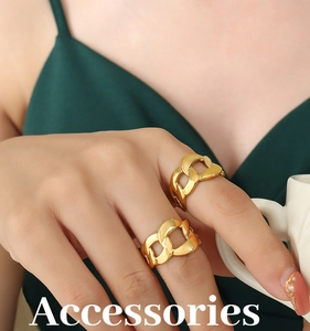 Close-up of chunky gold-plated Cuban link rings worn on fingers holding a white cup