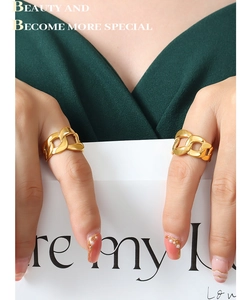 Detail of 18K gold plated chunky Cuban link chain rings on a female model wearing dark green