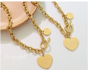 Détail macro du collier chaîne dorée avec pendentif cœur et fermoir à bascule OT