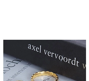 Vue macro d'une bague dorée ondulée aux bords dentelés sur un fond de style minimaliste
