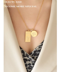 Gros plan d'un collier doré en acier inoxydable avec pendentifs carré et rond