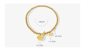 Détail du fermoir OT et du pendentif cœur gravé sur une chaîne à maillons dorée