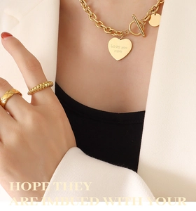 Gros plan du pendentif cœur doré avec gravure Love You More et fermoir OT robuste