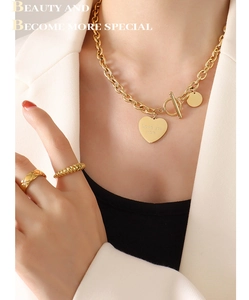 Détail du collier doré avec pendentif coeur, fermoir OT et grosse chaîne sur modèle