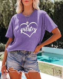 Detail of purple Pilates t-shirt featuring a white heart graphic and crew neck design