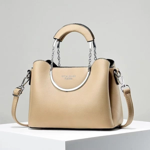 Close-up of beige lychee grain leather handbag featuring circular metal chain handles