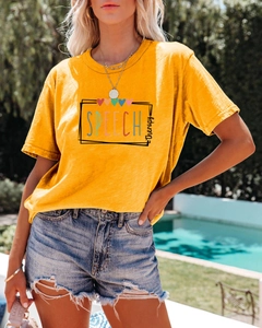 Gros plan du t-shirt jaune Speech Therapy avec short en jean près d'une piscine ensoleillée