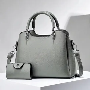 Gray lychee grain leather handbag set with matching pouch on minimalist stone base