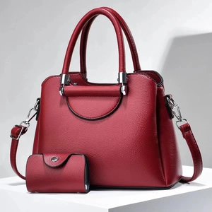 Detail of burgundy lychee leather handbag with matching coin purse and silver hardware