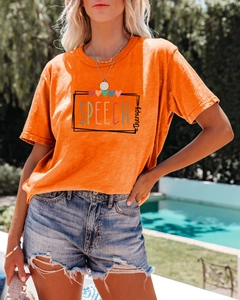 Gros plan sur un T-shirt orange speech therapy avec un short en jean effiloché