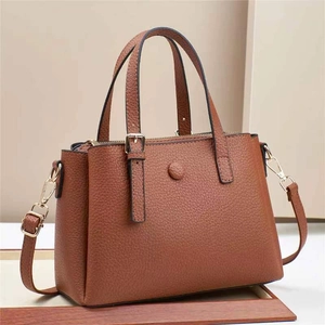 Detail of caramel pebble leather handbag with dual handles and gold metallic hardware