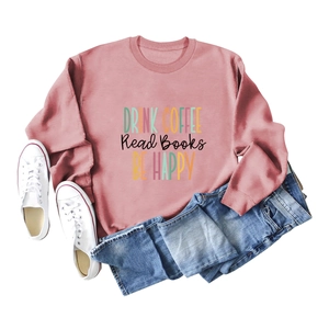 Close-up of pink crewneck sweatshirt with Drink Coffee Read Books print and blue jeans