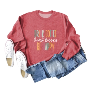 Detail of red crewneck sweatshirt featuring Drink Coffee Read Books Be Happy printed text