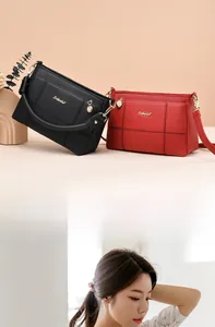 Detail of stitched litchi grain leather handbags in black and red with gold hardware