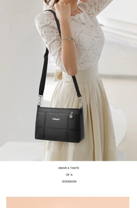 Detail of black pebbled leather crossbody bag with silver logo and quilted stitching
