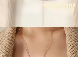 Dettaglio della collana a sfere in oro rosa su uno sfondo di maglione beige