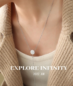 Dettaglio della collana lunga con ciondolo girasole in zirconi su maglia beige