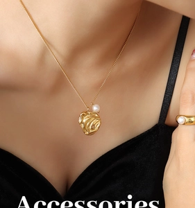Dettaglio della collana e dell'anello in titanio dorato con perle irregolari sulla pelle