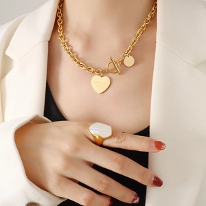 Collier chaîne dorée avec pendentif cœur et bague en nacre portés par un mannequin