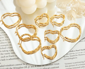 Détails de boucles d'oreilles cœur torsadées dorées de tailles variées sur un miroir
